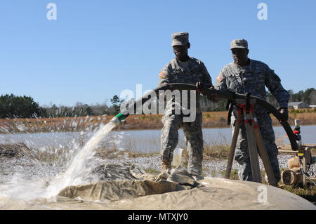 Pfc. L'vonta Richardson (left) and Sgt. Marvin Dicks, water purification specialists assigned to the 351st Aviation Support Battalion, Alpha Company, Hartsfield South Carolina, works together to create water flow in the tactical water purification system at Camp Shelby Jan. 31, 2017. The TWPS can purify 1,500 gallons of fresh water in an hour and 1,200 gallons of saltwater in an hour. (U.S. Air National Guard Photo by Airman 1st Class Kiara N. Spann/Released) Stock Photo