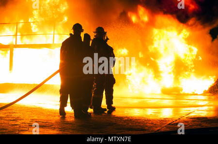 JOHANNESBURG, SOUTH AFRICA - MAY, 2018 Firefighters standing in front of fire with hose during fighting training exercise Stock Photo