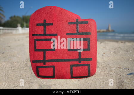 Double happiness in chinese language on a painted stones over the beach Stock Photo