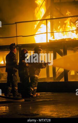 JOHANNESBURG, SOUTH AFRICA - MAY, 2018 Firefighters spraying water at burning structure during firefighting training exercise Stock Photo