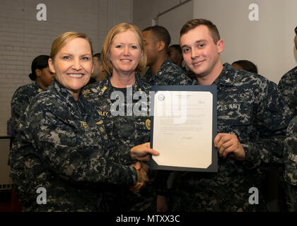 NEWPORT NEWS, Va. (Jan. 04, 2017) – Culinary Specialist 3rd Class Vincent Collins, assigned to Pre-Commissioning Unit Gerald R. Ford (CVN 78), receives his frocking letter from Cmdr. Julie Treanor, Ford’s supply officer, and Ford’s command master chief Laura Nunley during a supply department frocking ceremony at Apprenticeship Hall.  More than 170 Ford Sailors advanced from the September Navy-wide advancement exam. (U.S. Navy photo by Mass Communication Specialist Seaman Joshua Murray) Stock Photo