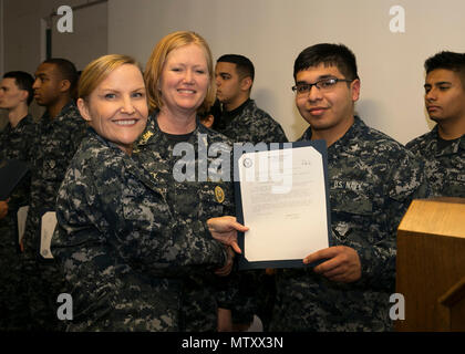 NEWPORT NEWS, Va. (Jan. 04, 2017) – Culinary Specialist 3rd Class Alfredo Rodriguez, assigned to Pre-Commissioning Unit Gerald R. Ford (CVN 78), receives her frocking letter from Cmdr. Julie Treanor, Ford’s supply officer, and Ford’s command master chief Laura Nunley during a supply department frocking ceremony at Apprenticeship Hall.  More than 170 Ford Sailors advanced from the September Navy-wide advancement exam. (U.S. Navy photo by Mass Communication Specialist Seaman Joshua Murray) Stock Photo