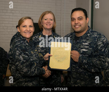 NEWPORT NEWS, Va. (Jan. 04, 2017) – Logistics Specialist 1st Class Daniel Silva, assigned to Pre-Commissioning Unit Gerald R. Ford (CVN 78), is announced as the Supply Department Sailor of the Quarter by Cmdr. Julie Treanor, Ford’s supply officer, and Ford’s command master chief Laura Nunley CVN 78 Command Master Chief, during an awards and quarters ceremony at Apprenticeship Hall. (U.S. Navy photo by Mass Communication Specialist Seaman Joshua Murray)(Image was altered for security purposes) Stock Photo