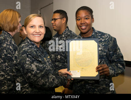 NEWPORT NEWS, Va. (Jan. 04, 2017) – Ship’s Serviceman Seaman Shangarcia Tennant, assigned to Pre-Commissioning Unit Gerald R. Ford (CVN 78), is announced as the Supply Department Bluejacket of the Quarter by Cmdr. Julie Treanor, Ford’s supply officer, and Ford’s command master chief Laura Nunley during an awards and quarters ceremony at Apprenticeship Hall. (U.S. Navy photo by Mass Communication Specialist Seaman Joshua Murray)(Image was altered for security purposes) Stock Photo