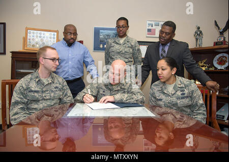 Col. Roman L. Hund, installation commander, signs an African American Heritage Month proclamation in his office Jan. 23, while Capt. Leo Barkardt, seated left, 2nd Lt. Jamecia Lazard, seated right, Chris Roach, standing left, Senior Airman Noelle Valentine, standing center, and Galen Williams, all members of the African American Heritage Month Council, look on. Throughout the month of February, the council will offer events to commemorate the significant role African Americans have had in the United States. (U.S. Air Force photo by Jerry Saslav) Stock Photo