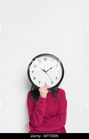 Woman holding clock over her face isolated on white Stock Photo