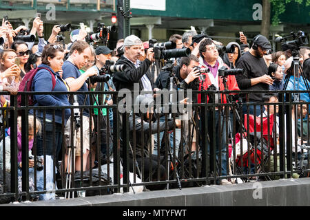 Photographers on the Tudor City overpass preparing to photograph the Manhattanhenge sun set. Manhattanhenge is where the rising or setting sun aligns with the street grid in Manhattan, New York City. Here it is as seen from 42nd Street in Manhattan in New York City. Stock Photo