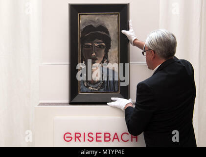 31 May 2018, Germany, Berlin: An employee at Villa Grisebach lifts the paiting 'Die Aegypterin' (lit. The Egyptian Woman) by Max Beckmann onto a pedestal before the auction. Its value is estimated at between 1.5 and 2 million euros. Photo: Soeren Stache/dpa Stock Photo