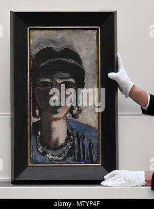 31 May 2018, Germany, Berlin: An employee at Villa Grisebach holding the paiting 'Die Aegypterin' (lit. The Egyptian Woman) by Max Beckmann on a pedestal before the auction. Its value is estimated at between 1.5 and 2 million euros. Photo: Soeren Stache/dpa Stock Photo