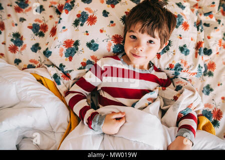 Smiling boy lying in bed Stock Photo