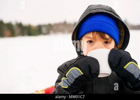 Boy standing in the snow drinking hot chocolate