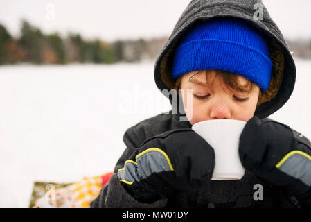 Boy standing in the snow drinking hot chocolate