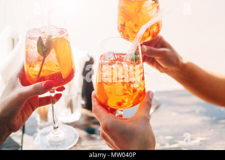 Three women making a celebratory toast with aperol spritz cocktails Stock Photo