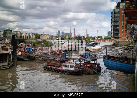 View looking east towards a distant Canary Wharf with live on houseboats in foreground and modern and old riverside apartments both sides. Stock Photo