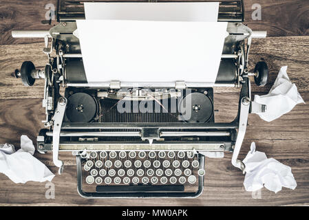 top view of old manual typewriter and crumpled sheets of paper on rustic wooden desk Stock Photo