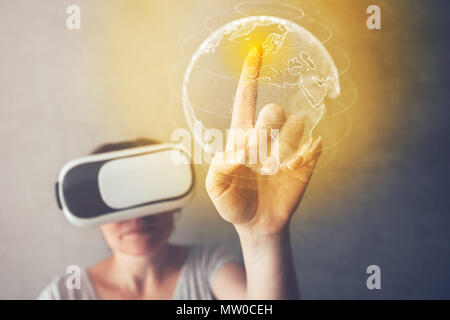 Woman immersed in virtual reality pointing to Great Britain on world map, female person using modern VR headset to experience 3d multimedia content Stock Photo