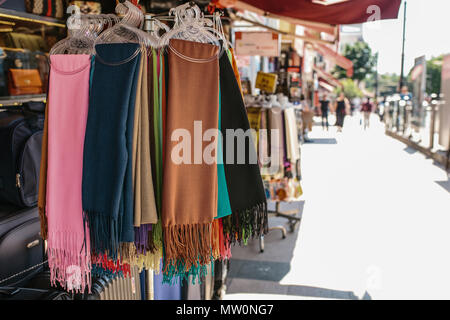 Stack of colorful stylish scarves or shawls on the hanger on display in the street vendor's booth, outdoor shopping district view during daytime. Stock Photo