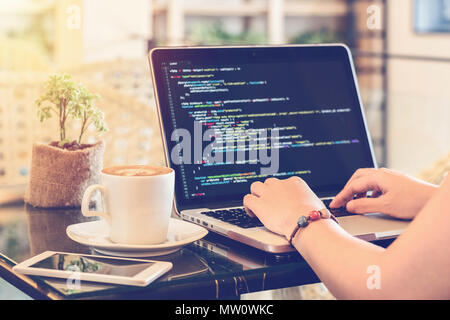 A programmer typing source codes in a coffee shop. Studying, Working, Technology, Freelance Work, Web Design Business, and Web Development Concept. Stock Photo