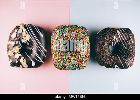 three square shape doughnut with different toppings on blue and pink background. sweet food and unhealthy eating concept Stock Photo