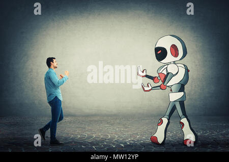 Young businessman holding fists ready to fight against robot. Rivalry between human and technology. Danger of losing the job, replacing the human work Stock Photo