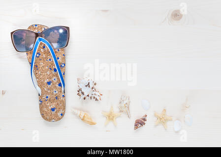 Concept of a beach holiday: slippers, sunglasses and seashells are on a light wooden surface. Top view, flat lay Stock Photo