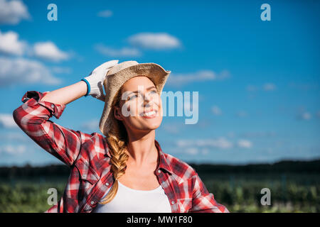 beautiful smiling young female farmer looking away while working on field Stock Photo