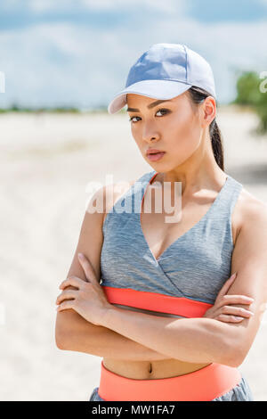 attractive brunette asian sportswoman with crossed arms posing in sportswear Stock Photo