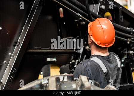 Industrial worker assembles agricultural equipment Stock Photo