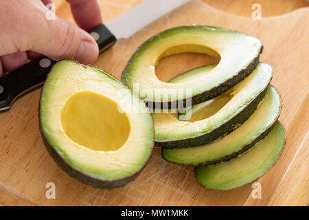 Sliced avocado with knife on wooden cutting board Stock Photo - Alamy