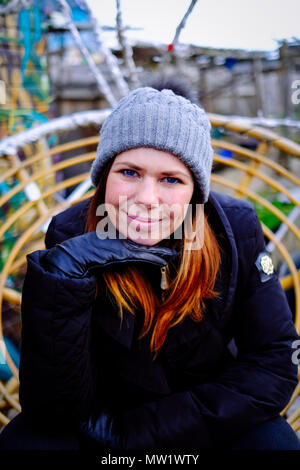A woman is posing with a hand under the chin at the Nomadic Community Garden off Brick Lane in Shoreditch, East London, England, UK. Stock Photo