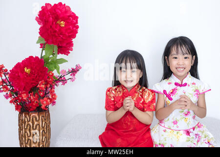 Asian Chinese little sisters wearing cheongsam with greeting gesture celebrating for Chinese New Year Stock Photo