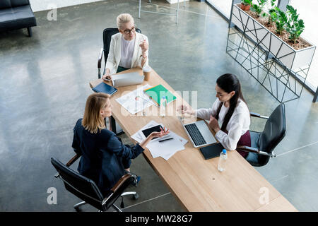 high angle view of three professional businesswomen discussing project at workplace Stock Photo