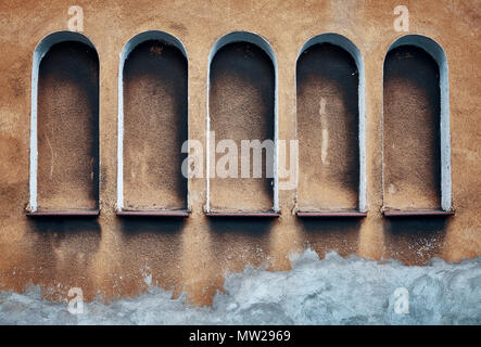 Five arched niches in an old textured wall, color toning applied. Stock Photo