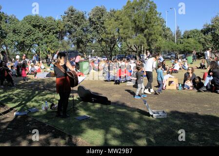 People relaxing in Sydney park, Bondi Australia. People enjoying day out sitting in park at Bondi Farmers Market. People of all ages sitting in sun. Stock Photo