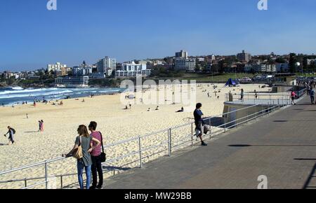 People enjoying sunny day at Bondi beach Sydney Australia. In view is Sydney cityscape of waterfront buildings or real estate in south side of Bondi Stock Photo