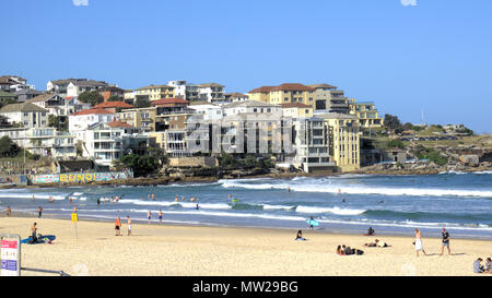 People enjoying sunny day at north side of Bondi beach in Sydney Australia. In view is Sydney cityscape of waterfront buildings or real estate. Stock Photo