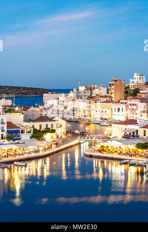 View of town and harbour at dusk, Agios Nikolaos, Lasithi Region, Crete (Kriti), Greece Stock Photo