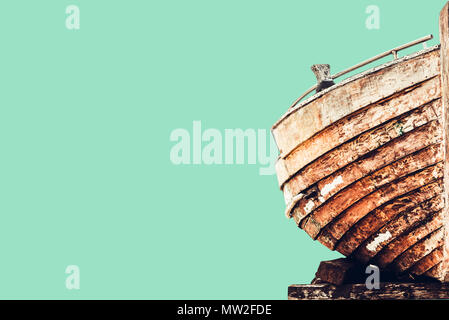 An old wooden boat. View of half of a wooden boat on a green pastel background, isolated. Stock Photo
