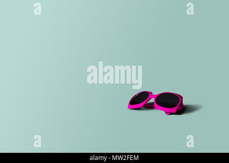 Pink sunglasses, pastel background. Minimalism. Holiday concept, sunbathing, rest. Sunglasses lie on a green-blue pastel background. Travel agencies. Stock Photo