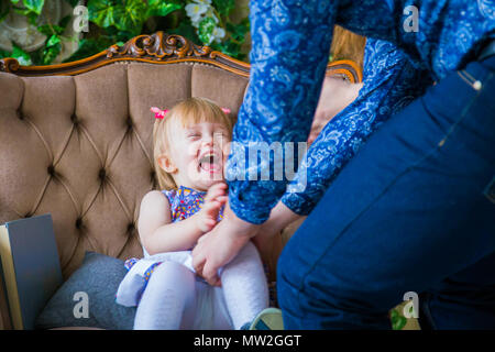 Happy young parents and their baby daughter playing togerher at home. Family, childhood and leisure concept Stock Photo