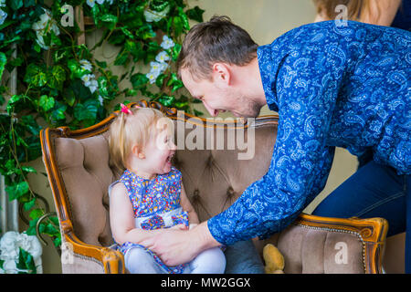 Happy young parents and their baby daughter playing togerher at home. Family, childhood and leisure concept Stock Photo