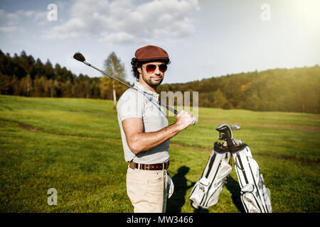 portrait of stylish golfer in glasses standing on golf course wi Stock Photo