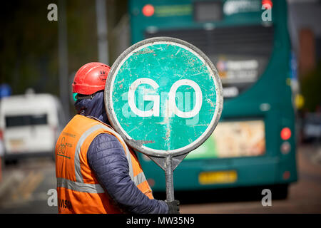 Construction worker using a manual traffic flow management using a stop go sign Oxford Road in Manchester Stock Photo