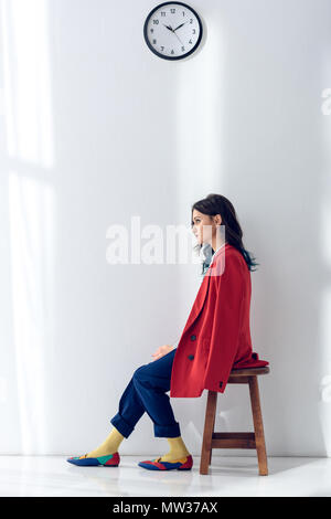 Pretty lady sitting on chair under clock Stock Photo