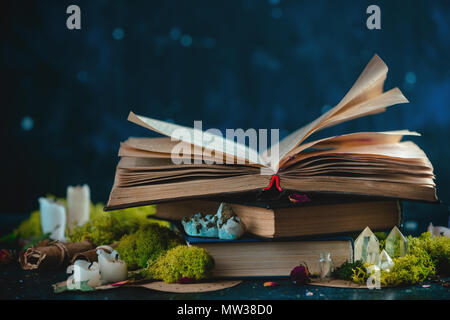 Open book with candles, crystals, and moss. Reading fantasy concept with copy space. Magical still life on a dark background with occult equipment. Stock Photo