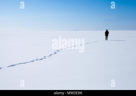 Lonely teenage girl walks along the endless snowfield Stock Photo