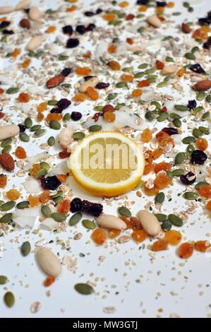 Randomized seeds and cereals on the white table, one lemon slice in front, selective focus, close up view Stock Photo