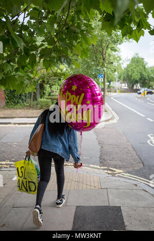 A young woman carries an oversized Happy Birthday balloon for a friend in Camberwell, on 30th May 2018, in London, England. Stock Photo