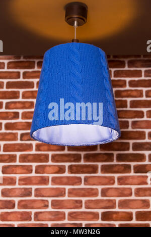 An original knitted lamp hanging on a wall against a brick wall background Stock Photo