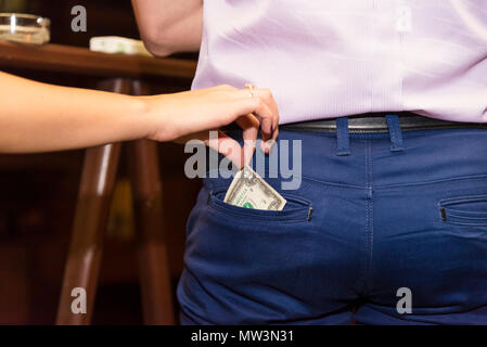 The girl's hand pulls money out of the man's pocket Stock Photo
